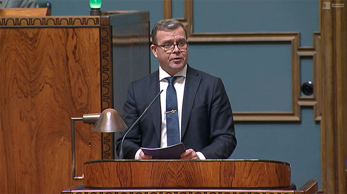 Pääministeri Petteri Orpoi seisoo eduskunnan istunosalin puhujapöntössä.