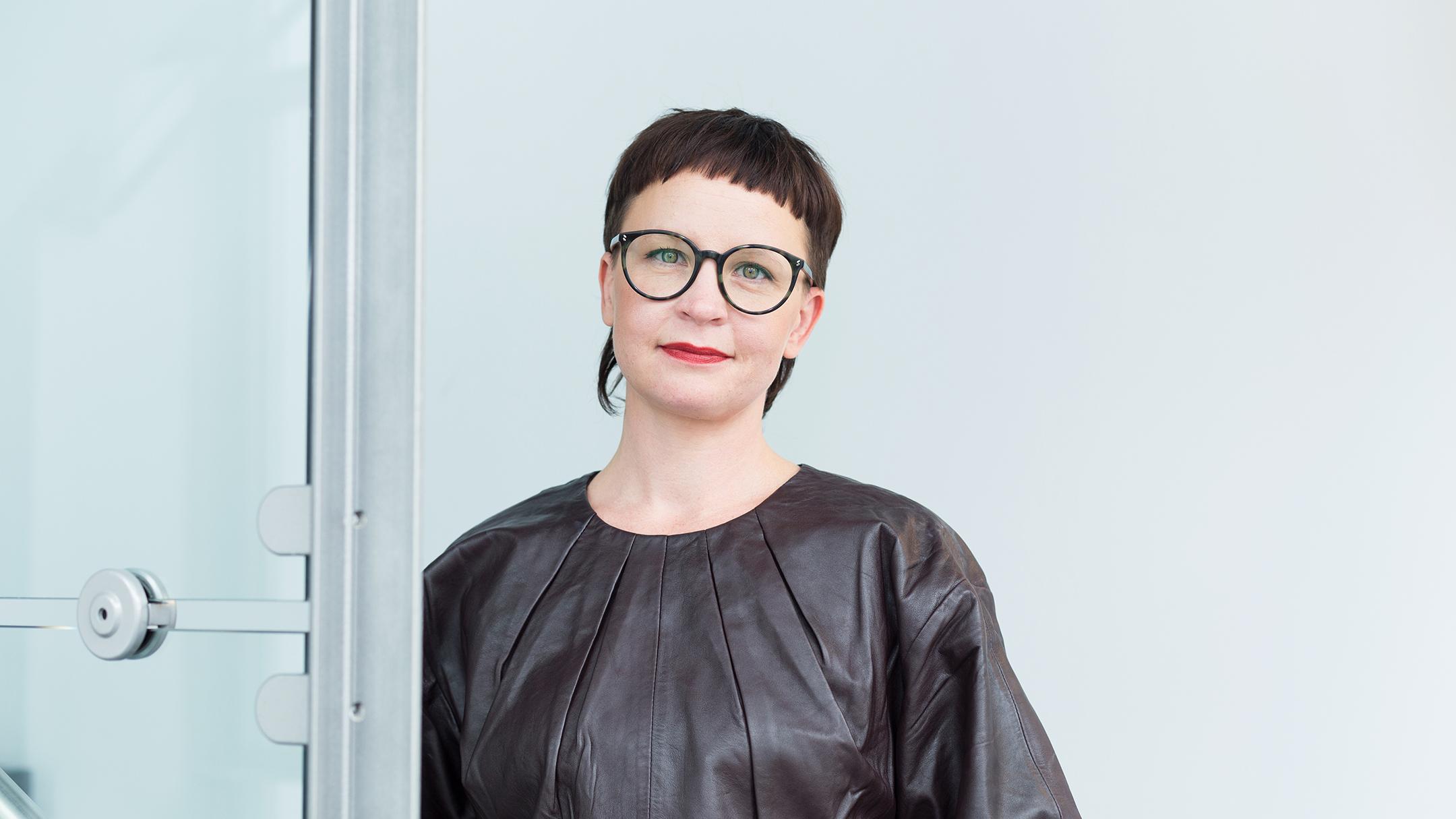 Kuvassa hymyilevä tummahiuksinen, silmälasipäinen Liisa Jokinen, joka on ollut sorvaamassa terapiatakuulakia sosiaali- ja terveysministeriössä.